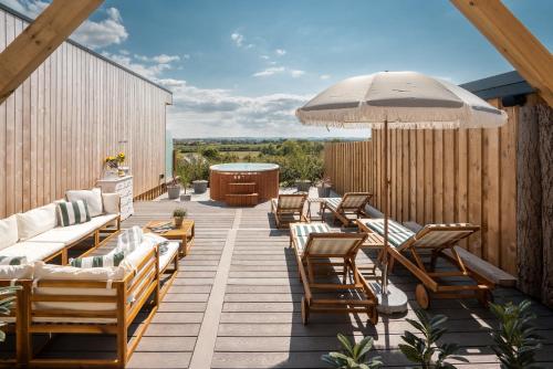 a deck with lounge chairs and an umbrella at Elements Suites in Middlezoy