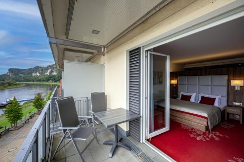 a bedroom with a balcony with a bed and a table at Rathener Hof by STEIGER Hotels in Kurort Rathen