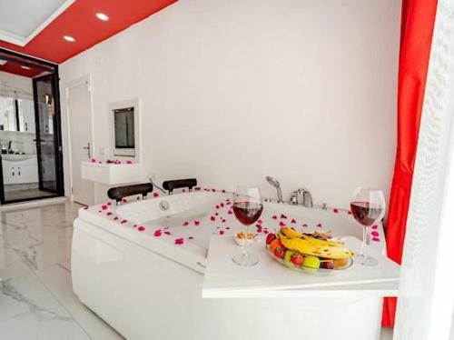 ein weißes Badezimmer mit einer Badewanne mit zwei Gläsern Wein in der Unterkunft Villa Alya 1-2-3 in Kalkan