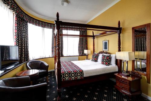 a bedroom with a canopy bed and a chair at The Imperial Hotel in Fort William