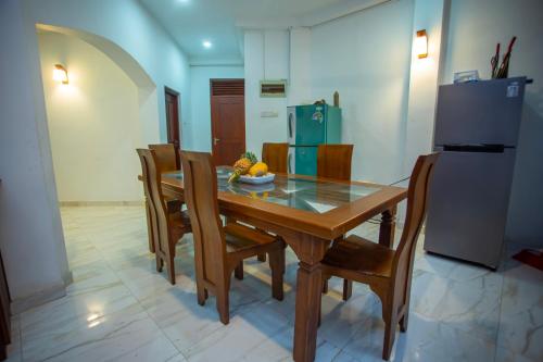 a dining room table with chairs and a refrigerator at Su Yu villa in Unawatuna