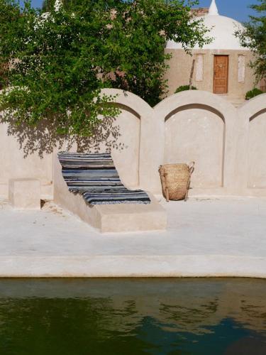 a stone bench next to a body of water at Gazrashek Siwa Hot spring& trips Haven in Siwa