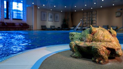 a statue of a turtle sitting next to a swimming pool at Zeitgeist Rathen by STEIGER Hotels in Kurort Rathen