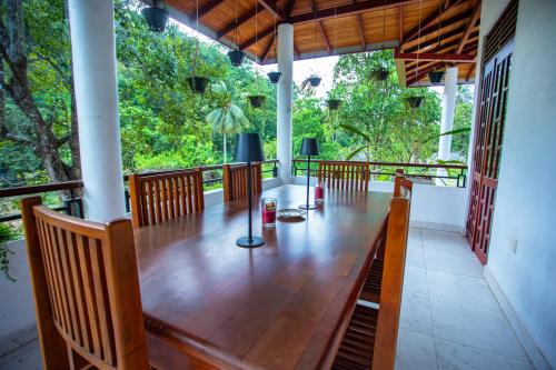 a porch with a wooden table and chairs at Su Yu villa in Unawatuna