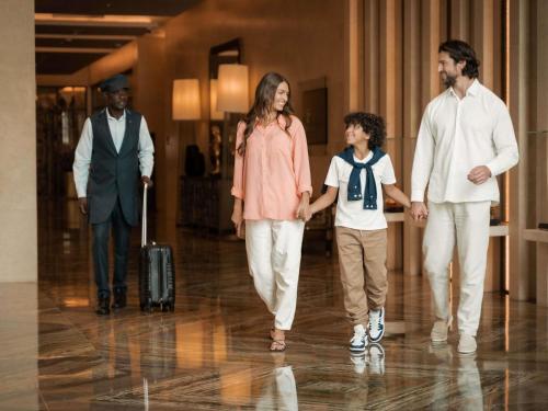 a family walking down a hallway with their luggage at Sofitel Dubai The Obelisk in Dubai