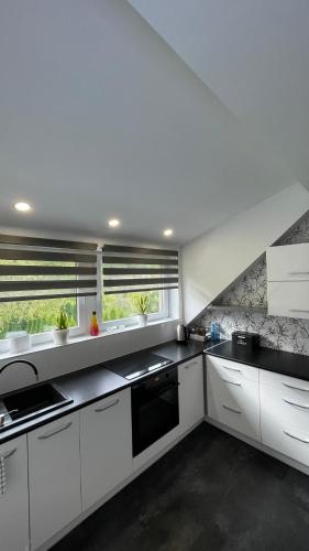a kitchen with white cabinets and a large window at Apartamenty Leśna Osiem in Jeżów Sudecki