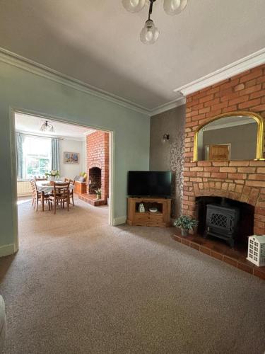a living room with a fireplace and a dining room at House on the Green Spacious-Super location in Derby