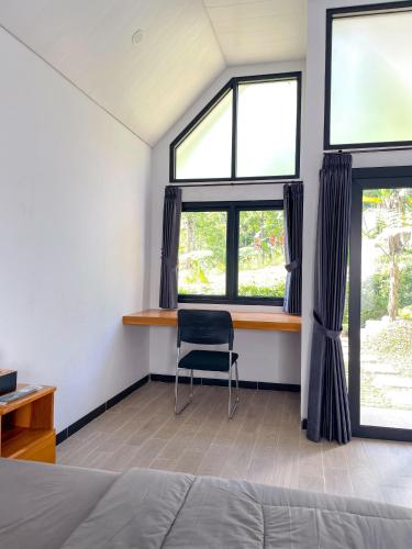a bedroom with a desk and two windows and a chair at Ulya Cabin Tawangmangu Private Pool Air Hangat in Tawangmangu