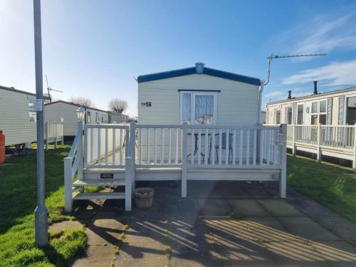 a white house with a gate and a porch at 8 Berth 3 bed caravan pet friendly TP56 in Chapel Saint Leonards