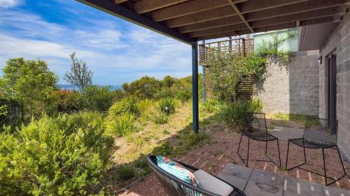 a patio with two chairs and a table and some bushes at One Mile Retreat in Anna Bay