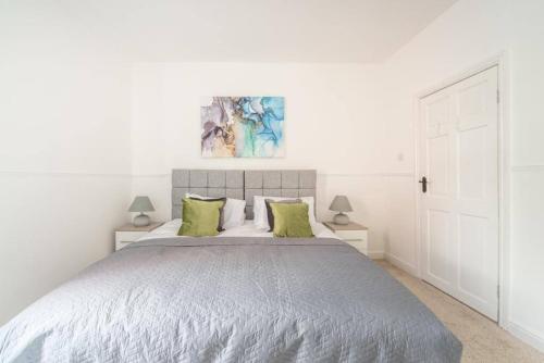 a white bedroom with a large bed with green pillows at Cosy home near Port of Hull in Hull