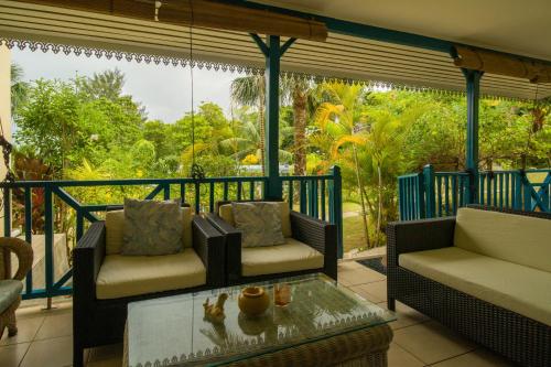 a screened in porch with two chairs and a coffee table at Residence Monte-Cristo in Anse Boileau