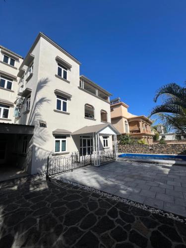 a large white building with a fence in front of it at Rooftop d'exception - calme et confort à Grand Baie in Grand Baie