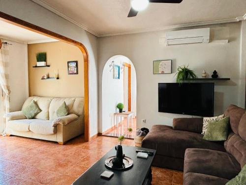a living room with a couch and a tv at Casa Zeus by SunshineClub in Los Alcázares