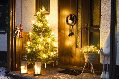 un arbre de Noël avec des lumières devant une porte dans l'établissement Reindeerly Cottage Hosted by Hygge Host, à Rovaniemi