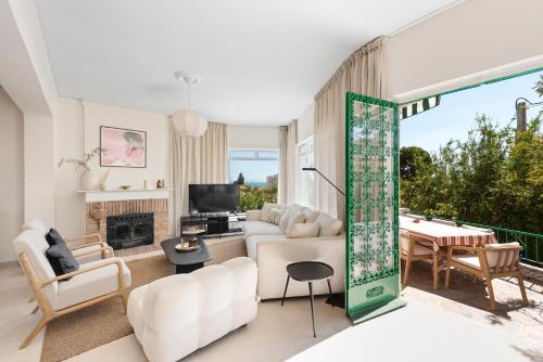 ein Wohnzimmer mit weißen Möbeln und einem großen Fenster in der Unterkunft Villa Victoria, Torremolinos in Torremolinos