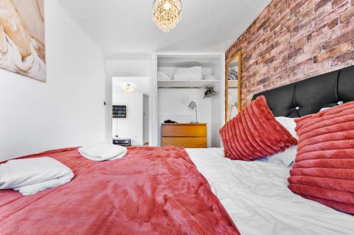 a bedroom with a red bed with a brick wall at Stunning 1 bedroom apartment in Dagenham in Dagenham