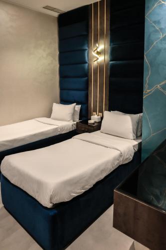two beds in a room with blue walls at Palazzo hotel in Kuwait