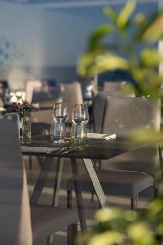 three wine glasses sitting on a table with chairs at Hotel Riva Del Sole in Giovinazzo