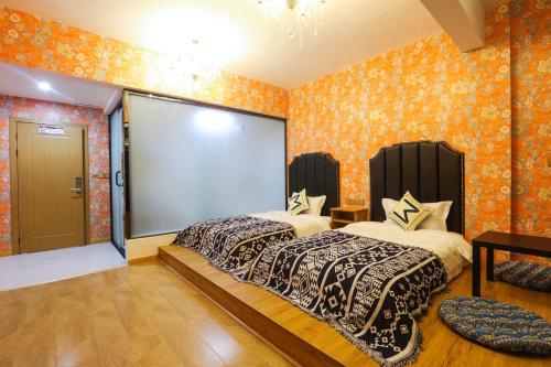 two beds in a room with orange wallpaper at XI SHANG YUN JIAN Inn in Hanqiyu