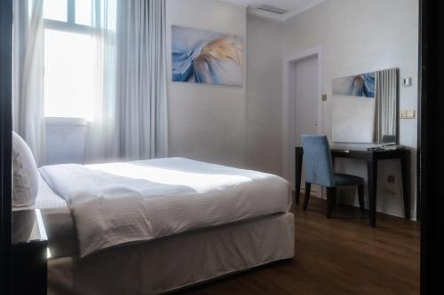 a bedroom with a bed and a desk with a chair at Palazzo hotel in Kuwait