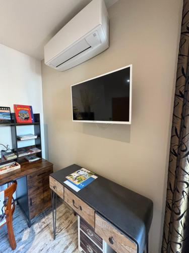 a living room with a table and a tv on a wall at Chambres d'Hôtes Villa Aquitaine in Bretagne-de-Marsan