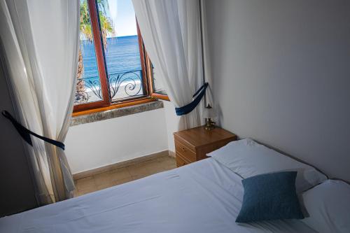 a bedroom with a bed and a window with the ocean at Palazzo Durante in Letojanni