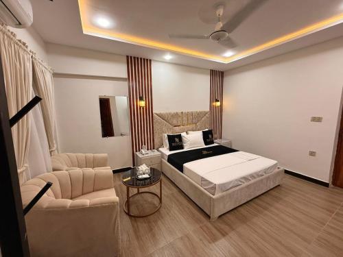 a bedroom with a bed and a couch and a chair at Nestopia Islamabad in Islamabad