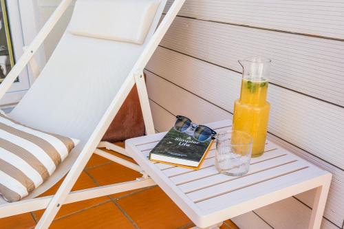 a book and a bottle of orange juice on a table at Zus House Stylish Pool Stay Near Lisbon & Beach in Parede