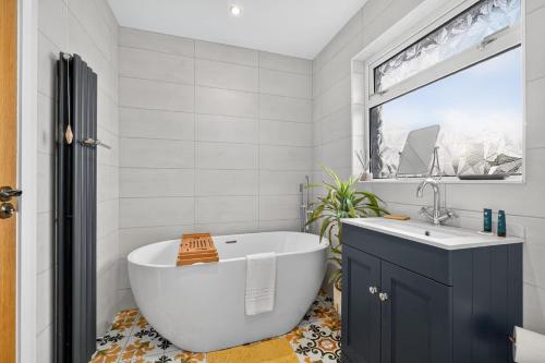a bathroom with a white tub and a window at Central Belfast Apartments Rosetta Residence in Belfast