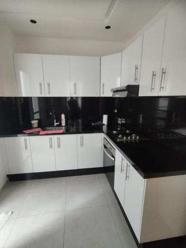 a kitchen with white cabinets and black counter tops at Superbe appartement A33 in Kenitra