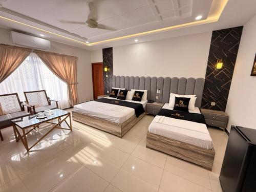 a hotel room with two beds and a couch at Nestopia Islamabad in Islamabad