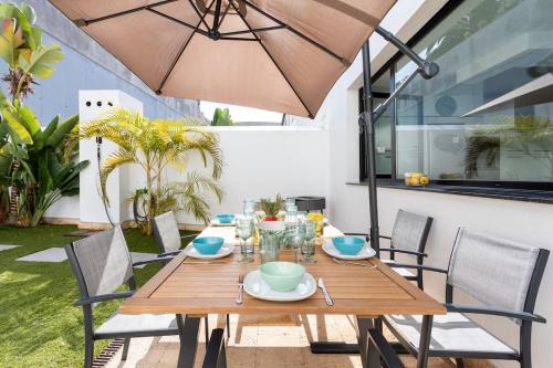 a wooden table with chairs and an umbrella at Villa Cleo, vistas de ensueño in San Miguel de Abona