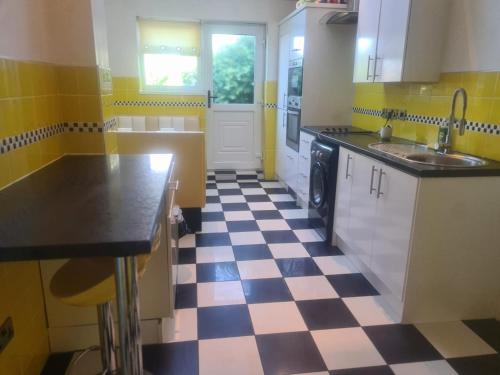 a yellow and white kitchen with a checkered floor at Northumberland Stays in Blythe