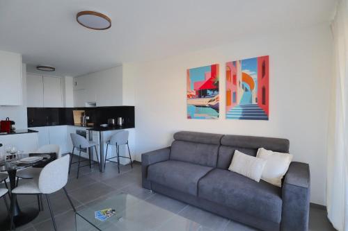 a living room with a gray couch and a kitchen at Sun Paradise SeaView&Terrace Parking&Pool in Beausoleil