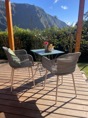 two chairs and a table on a deck at Le cottage in La Plaine des Palmistes