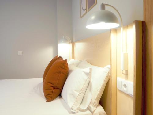 a bedroom with a bed with white pillows and a light at Apartamentos Laurel in Logroño