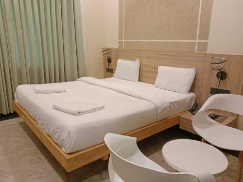 a bedroom with a bed with two chairs and a table at Pipul Ocean View Resort in Puri