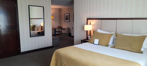 a hotel room with a large bed and a mirror at abba Presidente Suites Santiago in Santiago
