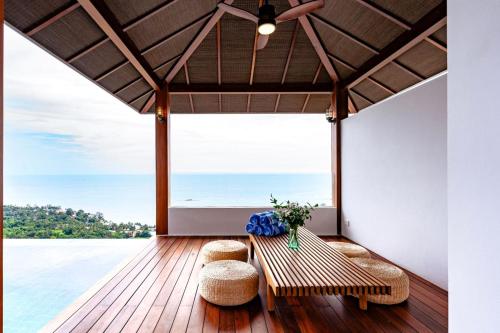 a porch with two benches and a view of the ocean at Anzhu Seamate Villa Samui in Amphoe Koh Samui
