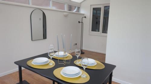 Un comedor con una mesa negra con platos y vasos amarillos. en Hebburn 3 bed House, en South Shields