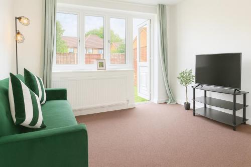 a living room with a green couch and a television at Modern 2BR Stay FREE WIFI FREE PARKING in Great Linford