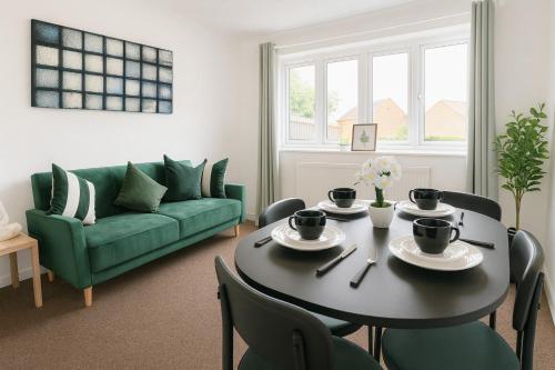 a living room with a table and a green couch at Modern 2BR Stay FREE WIFI FREE PARKING in Great Linford