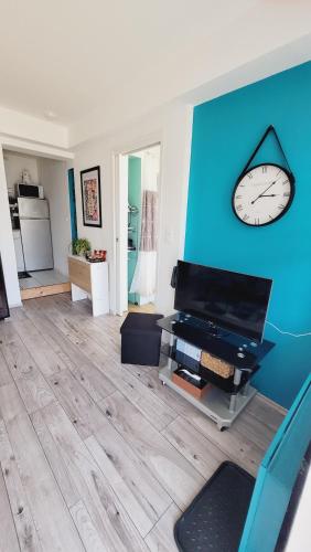 a living room with a clock on a blue wall at Le ptit Cosy appartement privatif in Bining-lès-Rohrbach