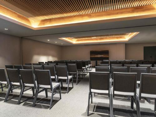 a conference room with rows of chairs and a screen at Costanero Hotel Montevideo - MGallery Collection in Montevideo