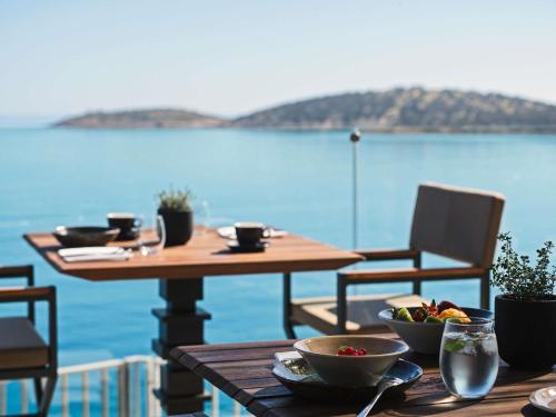 a table with bowls of food on top at NIKO Seaside Resort MGallery in Agios Nikolaos