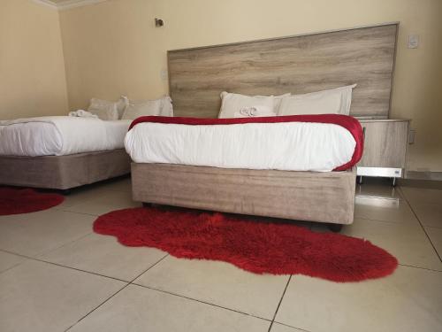 two beds in a hotel room with red rugs at Classy Guest House in Johannesburg