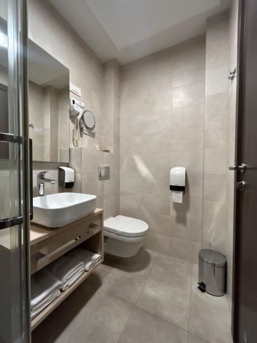 a bathroom with a white toilet and a sink at Hotel Gallus in Sesvete