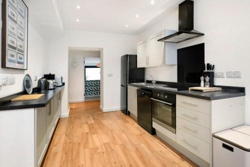 a kitchen with white and black appliances and wooden floors at Pinewood Lodge in South Brent