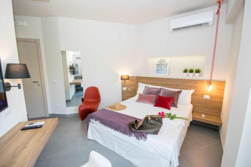 a bedroom with a bed and a red chair at Il Muro Vecchio Studios in Giardini Naxos